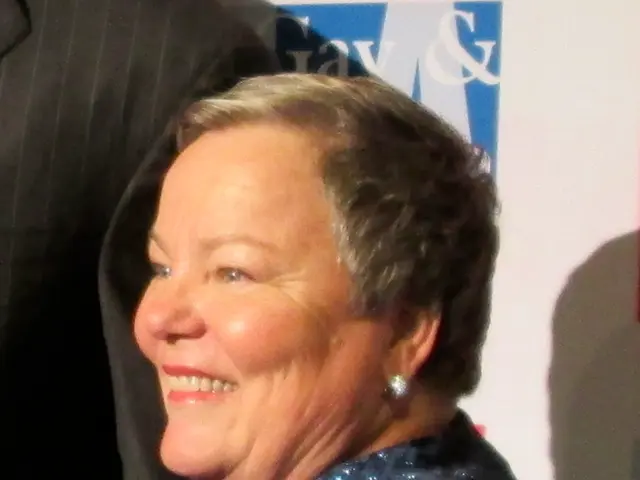 A woman is smiling she wore dress and also ear rings.