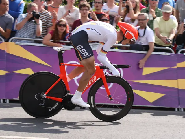 This man wore helmet and riding a bicycle. These are audience. This man is holding a camera.