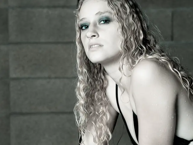 A woman is sitting at the right side. She has blonde hair and she is wearing a black dress. There...