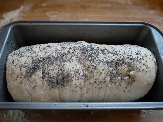 This picture shows a flour dough in a vessel and we see some seeds on it on the table.